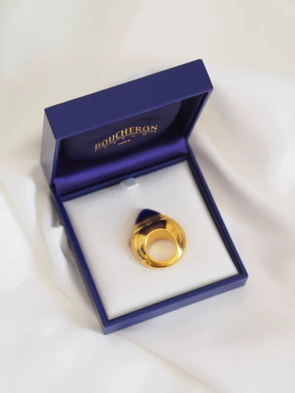Vintage Boucheron Jaipur brooch-style perfume bottle in gold with blue cap, in original blue box, photographed on white fabric