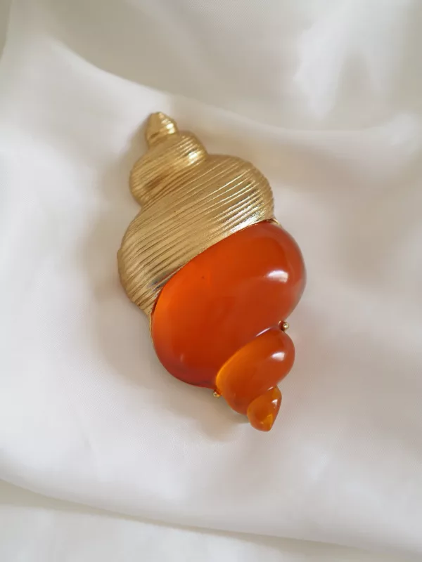 Vintage Dior Dune shell brooch in gold-tone metal and amber resin, designed by Robert Goossens, on white fabric background