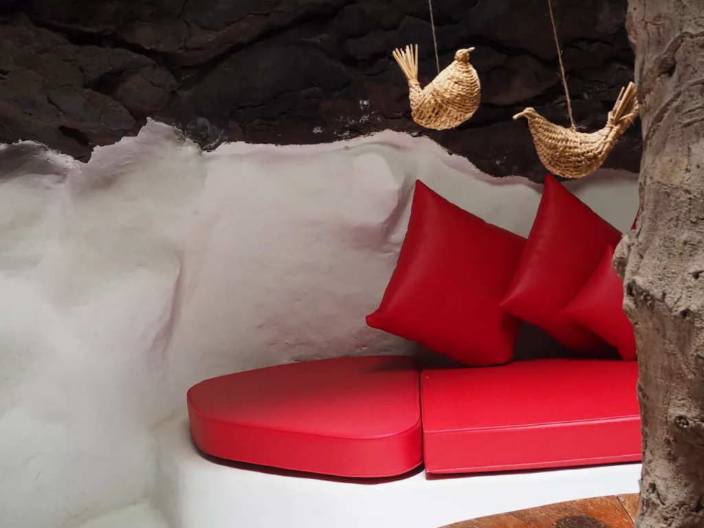 Interior view of César Manrique's foundation in Lanzarote with red sofa and rock walls.